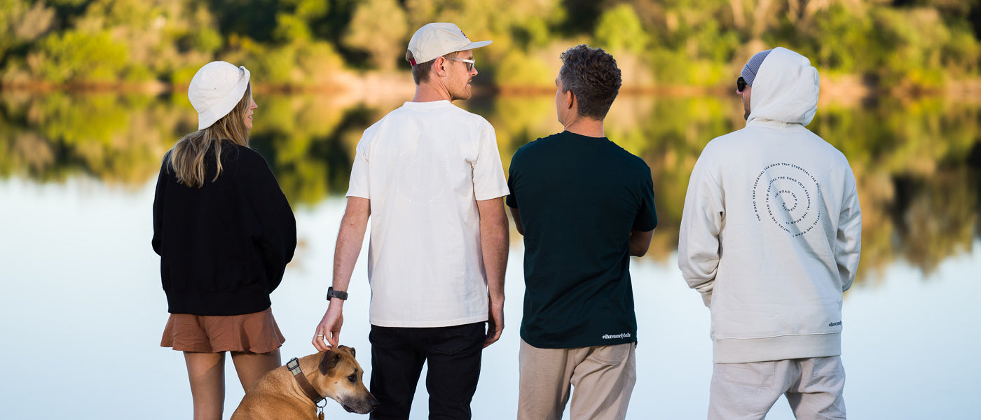 Four people with a dog standing by a lake.