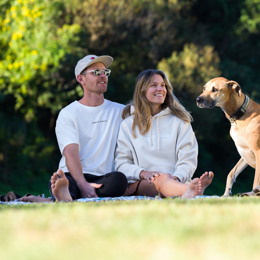 A couple sitting on the grass with a dog.