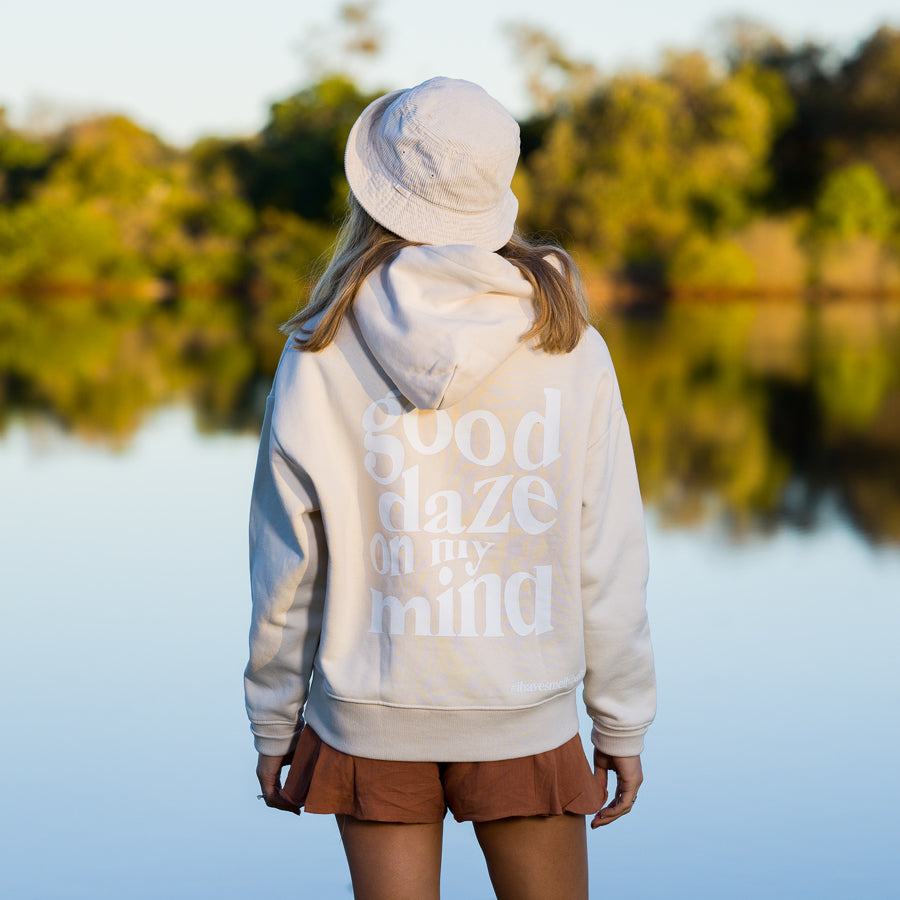A woman standing by a lake, wearing a hoodie that says "good daze on my mind.